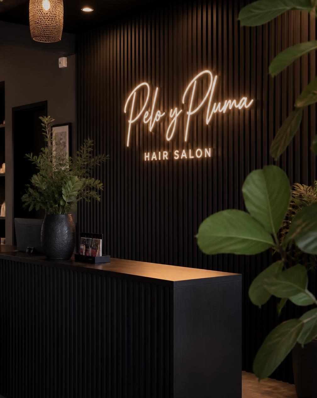 Warm white neon salon logo sign on a dark slatted wood reception wall